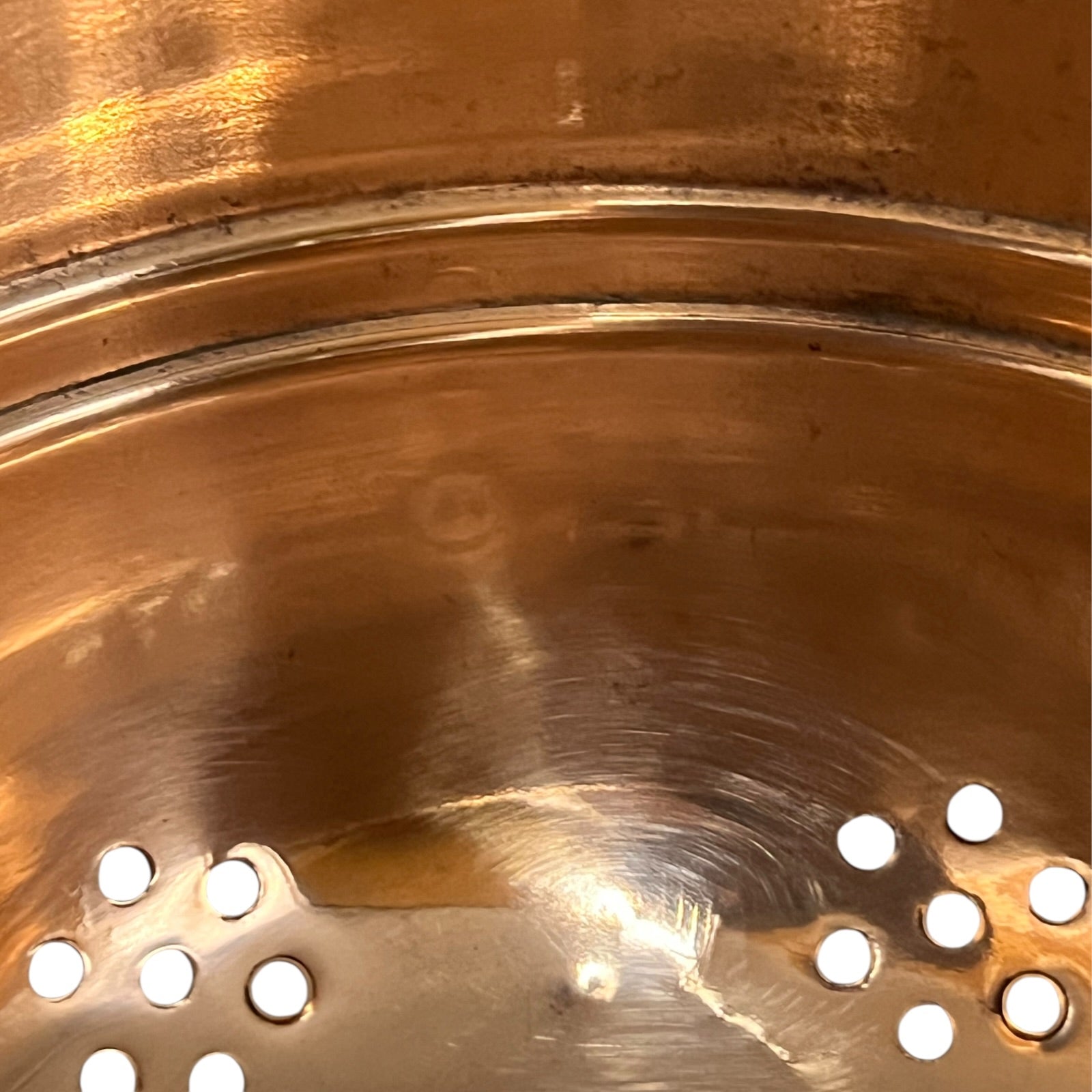 Copper colander with brass handles and feet on a white background