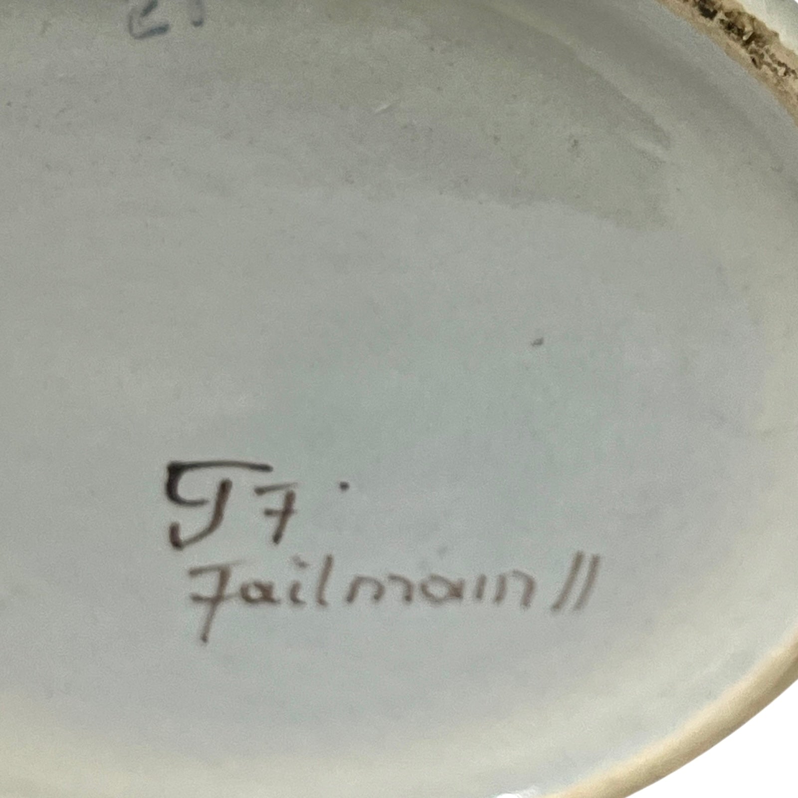 Ceramic pot base with a signature on a plain background