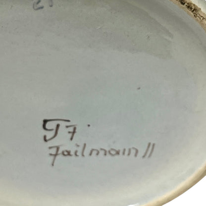 Ceramic pot base with a signature on a plain background