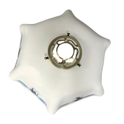 Close up of a white glass lamp shade with decorative design on a white background