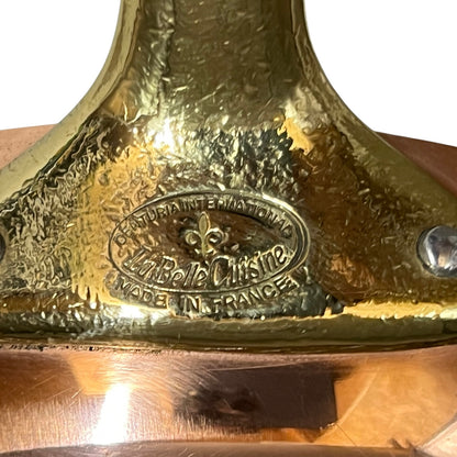 Close-up of a polished brass or bronze metal surface with an embossed oval logo reading 'Celtic International La Belle Cuisine Made in France' and a fleur-de-lis symbol.
