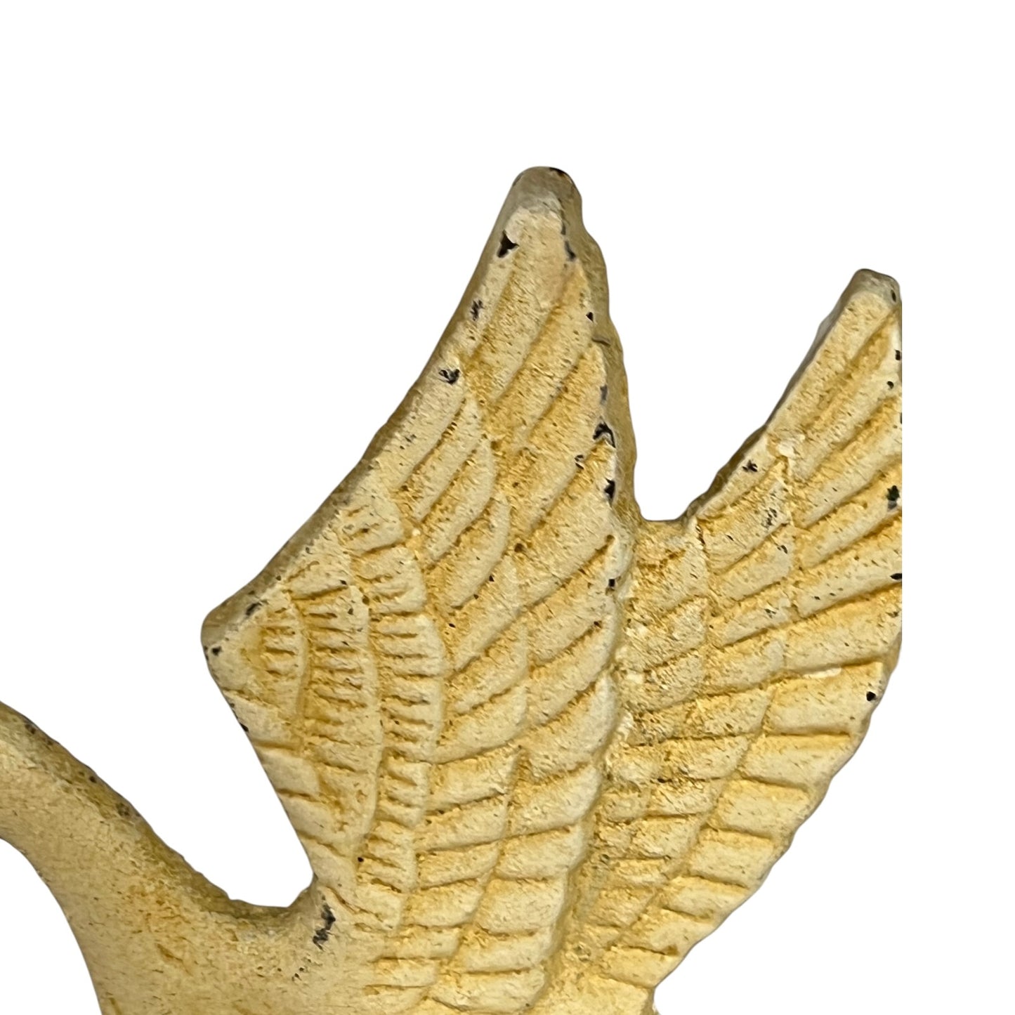 A close-up of a textured, winged decorative object in a warm beige or cream tone against a plain white background.