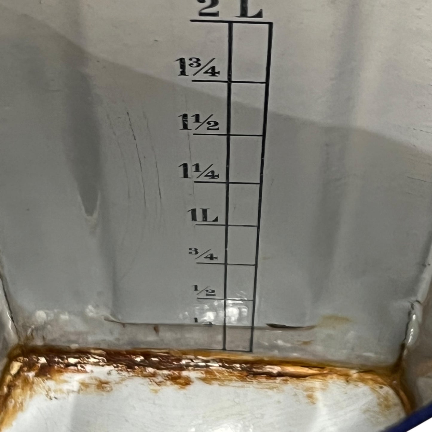 Inside of a French vintage enamel irrigator pot showing a rusty rim and some measurements 