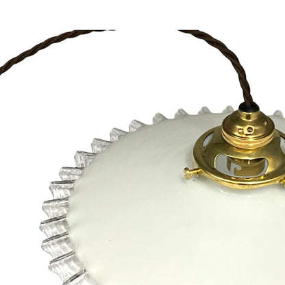 close up of brass ceiling light fixture with white glass shade on a white background