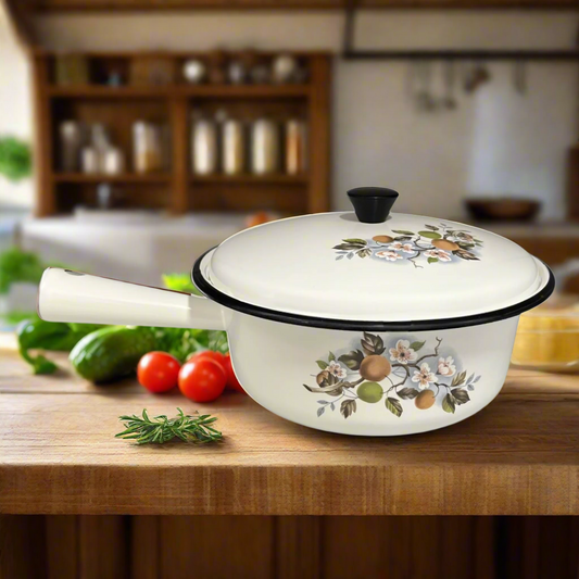 White enamel saucepan and lid with floral design on a wooden table in a rustic kitchen