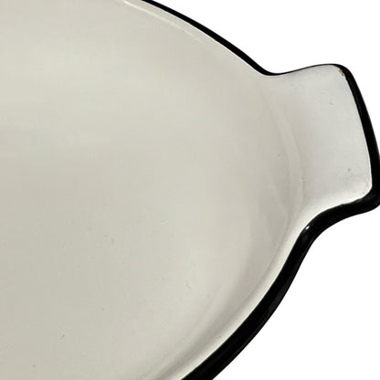 Close-up of a enamel baking dish with a black rim on a white background