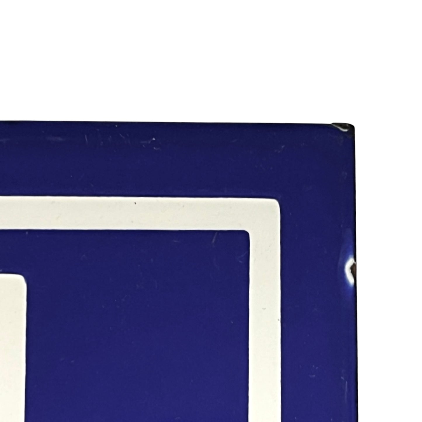 Close-up of a blue and white geometric sign or panel corner against a white background.