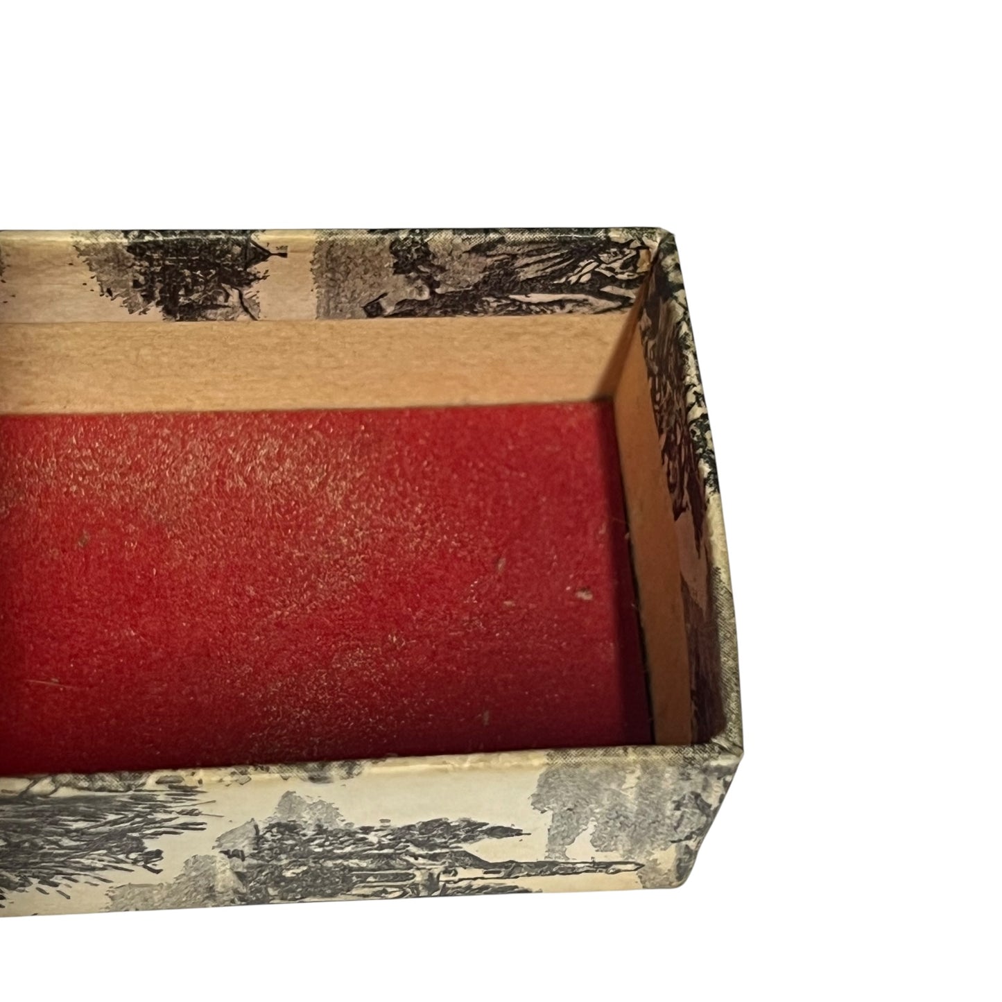 A close-up of an open rectangular box with a red velvet-like interior and a patterned exterior featuring a beige background with black and gray scenic illustrations.