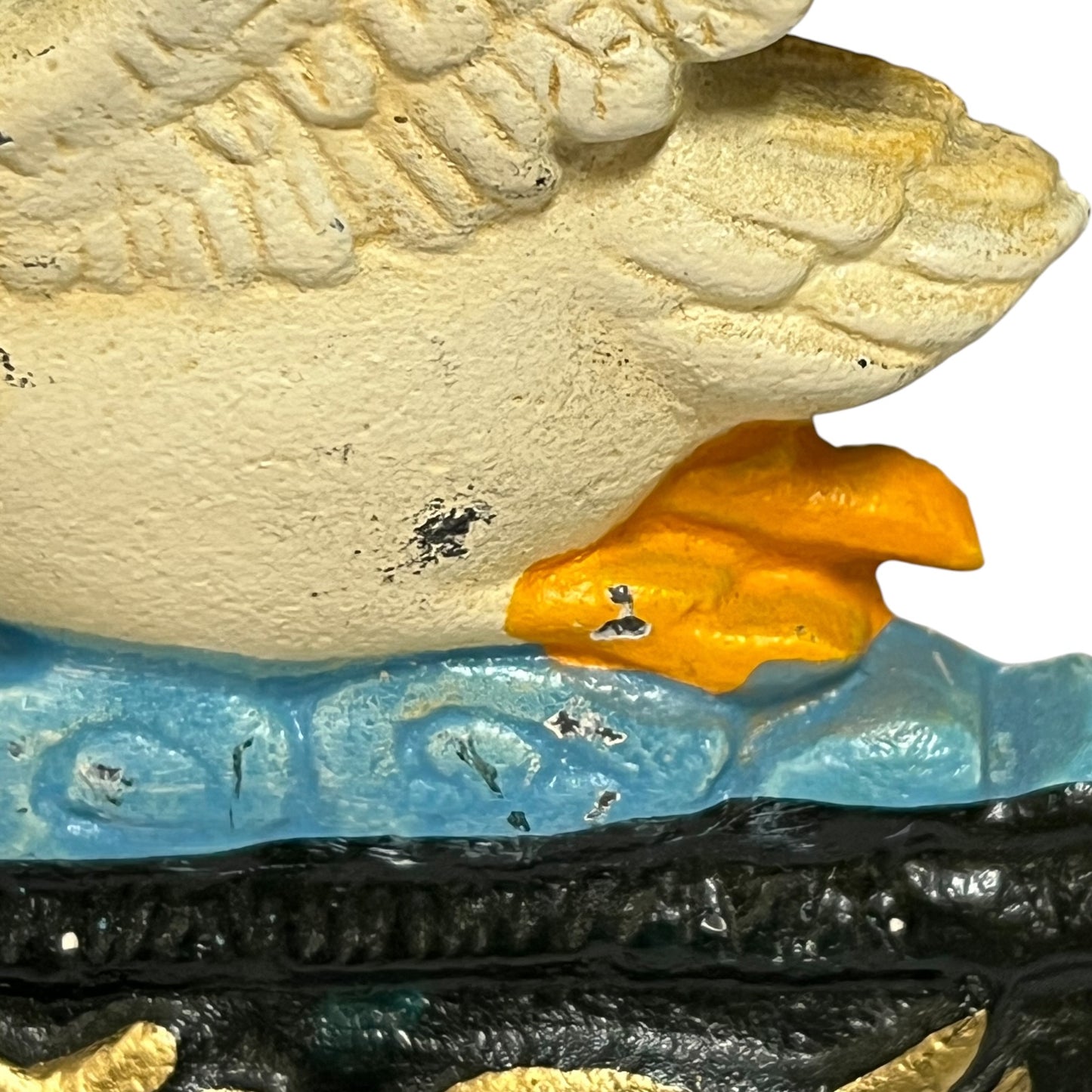 Close-up of a decorative sculptural object featuring a large textured cream-colored top section, a translucent light blue middle band, and a glossy black lower section with gold accents, against a white background.