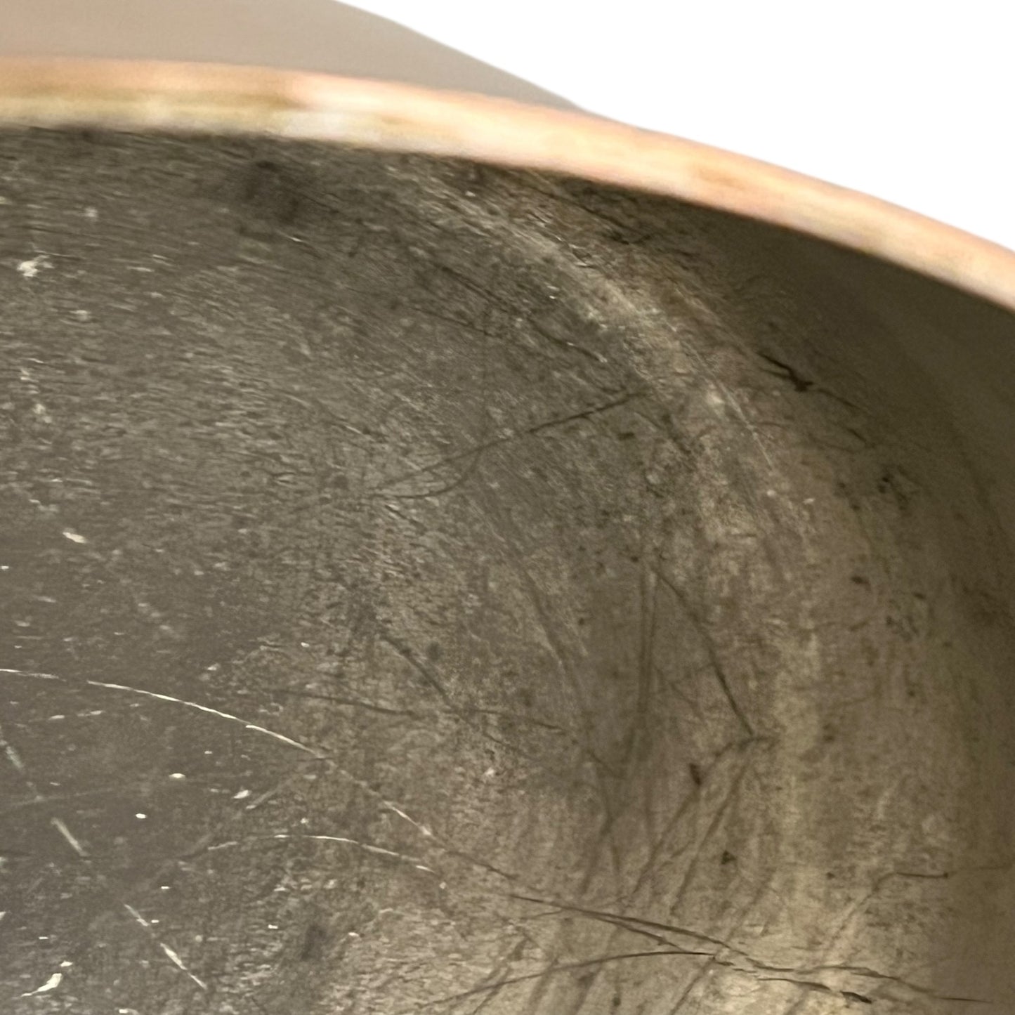 Close up of the inside of a French copper pan with tin lining on a white background