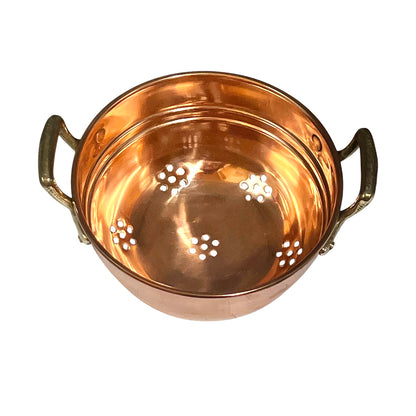 A copper colander with two side handles and perforated holes on the bottom, shown from a top-down angle on a white background.