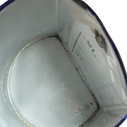 Close up of  French vintage enamel planter with a flat back and a spout on a white background