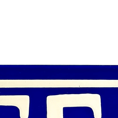 A close-up of a blue and white door number showing a bold royal blue area with a white horizontal stripe and white geometric shapes below.