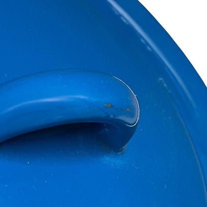 Close-up of a bright blue enamel lid featuring a curved carrying handle, showing minor scuffs on the surface.