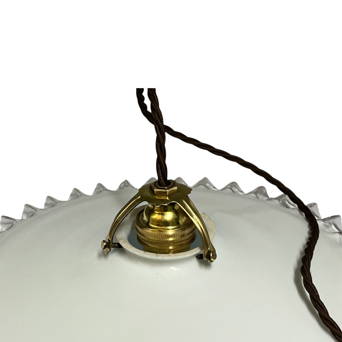 Close-up of a vintage pendant light fixture with a white glass shade, a brass metal canopy, and a dark brown hanging cord against a white background.