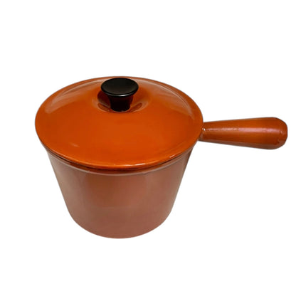 Rust coloured enamelled cast iron saucepan with lid on a white background