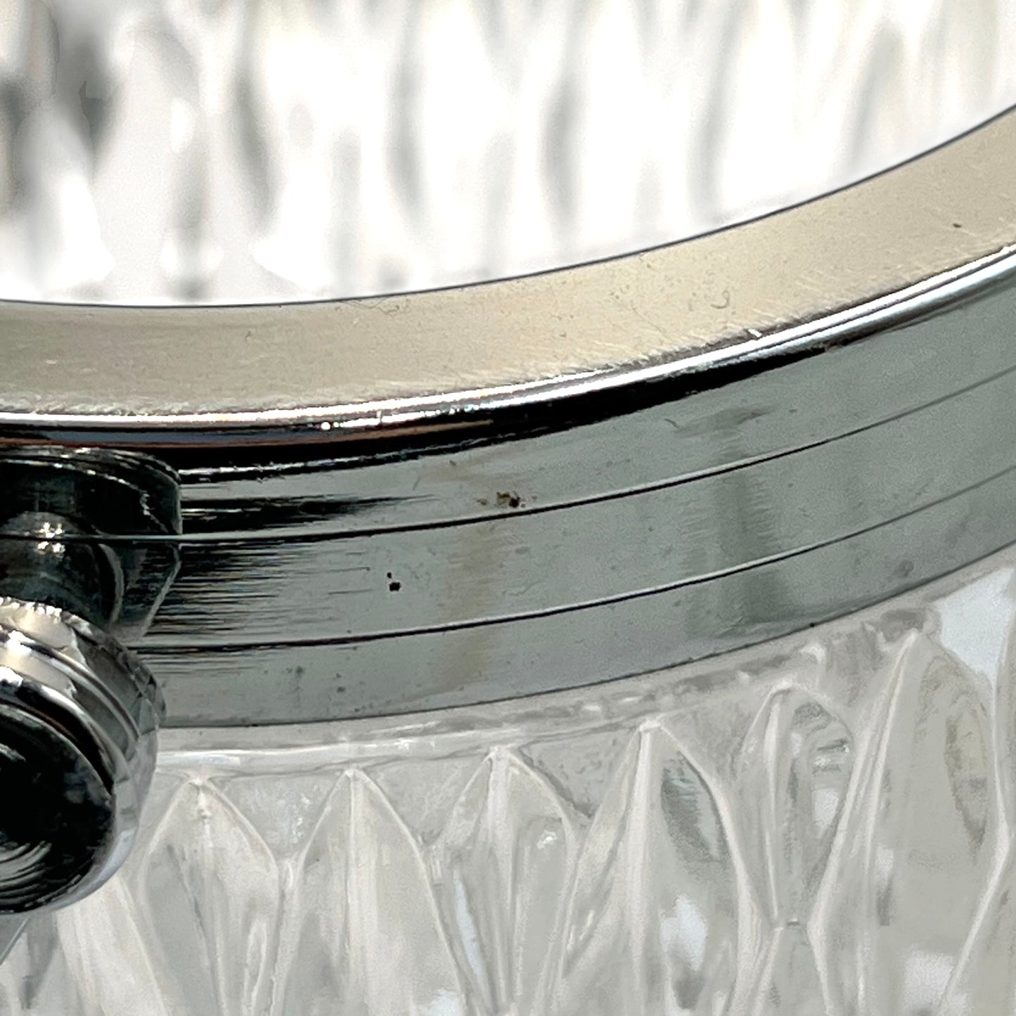 Close up of a French vintage glass ice bucket with a silver coloured collar and a handle on a white background 