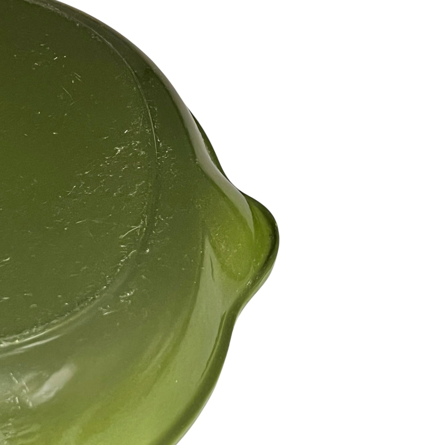 Close-up of a green Le Creuset cast iron skillet on a white background 