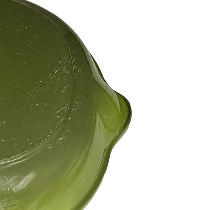 Close-up of a green Le Creuset cast iron skillet on a white background 