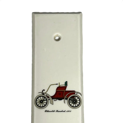 Close up of fingerplate with vintage car illustrations on a white background