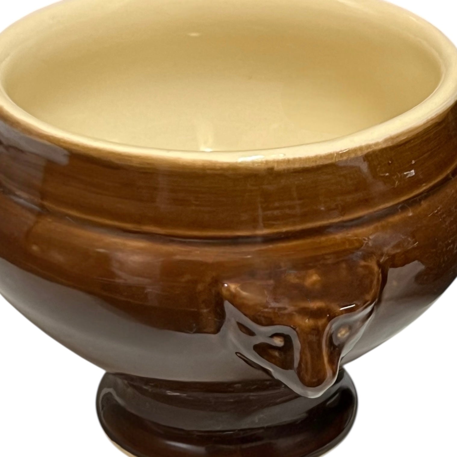 Brown ceramic bowl with decorative handles on a white background