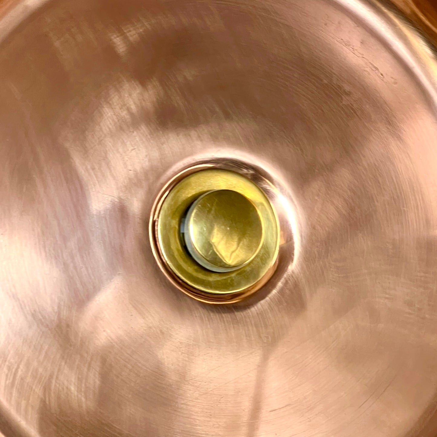 Close up of brass drain pop up style in a copper sink 