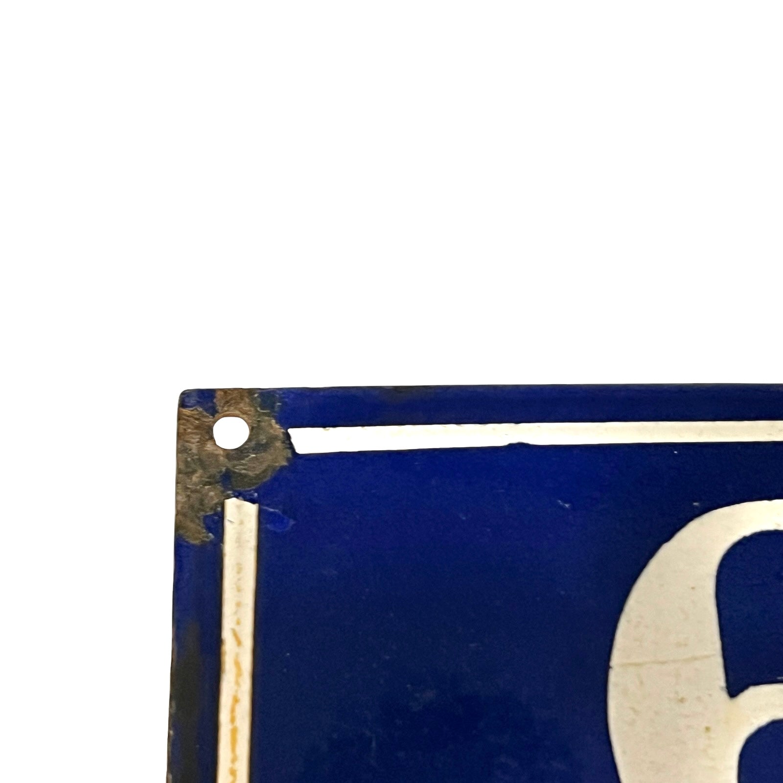 Close-up of a vintage blue enamel sign with a white painted border and a large white numeral, showing worn corners and a mounting hole.