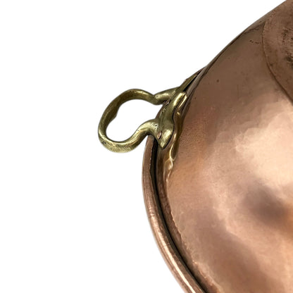 Close-up of a bronze or copper pot with a brass handle on a white background