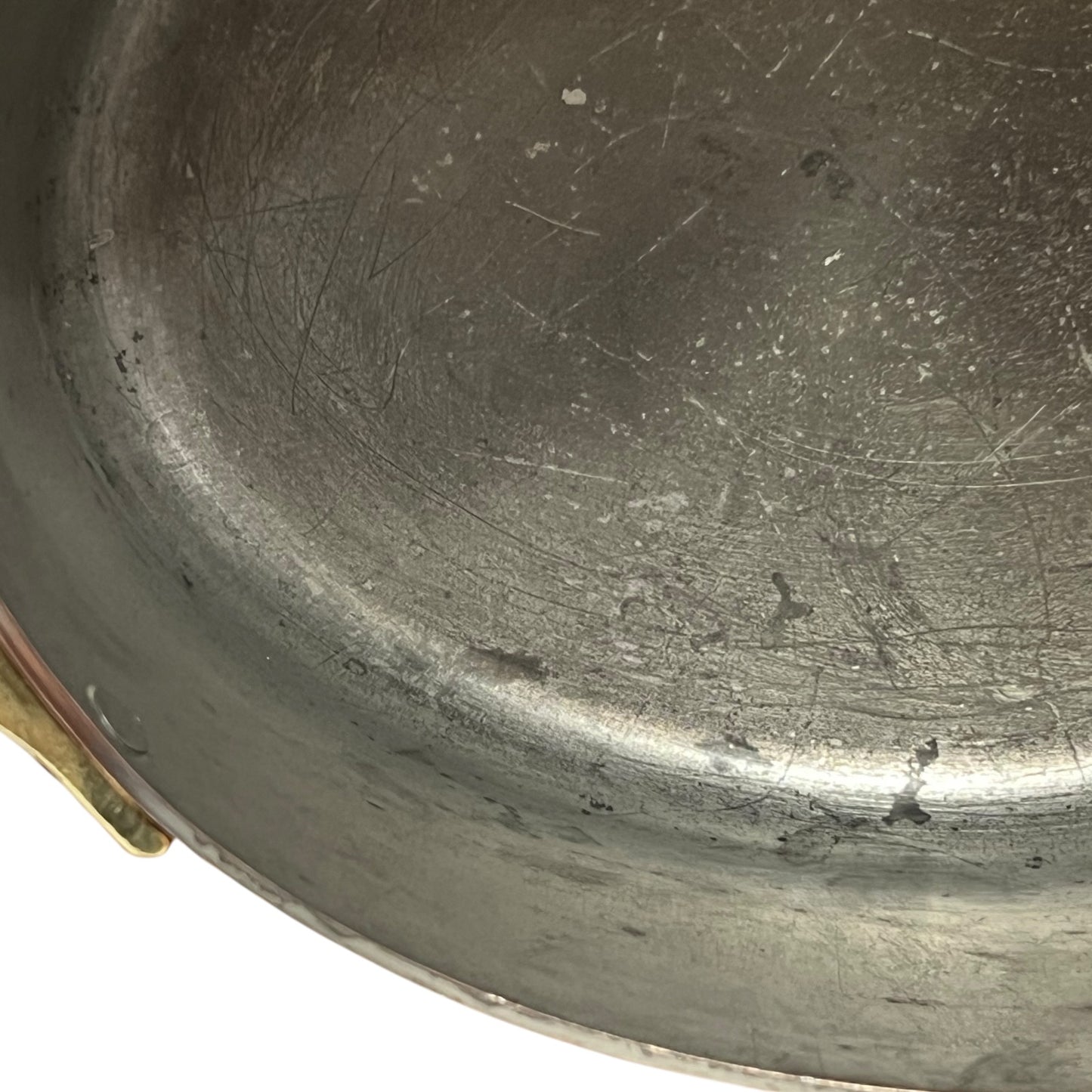 Close up of the inside of a French copper pan with tin lining on a white background
