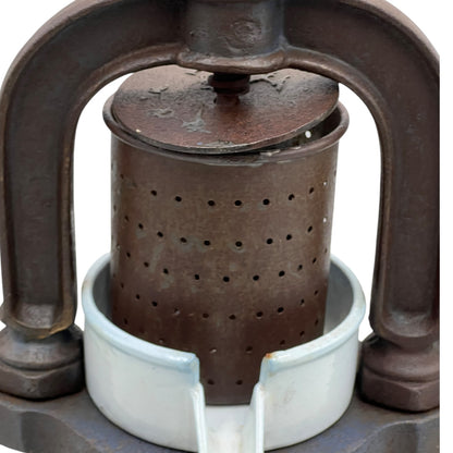 Close-up of a vintage French fruit press with an enamel pot on a white background