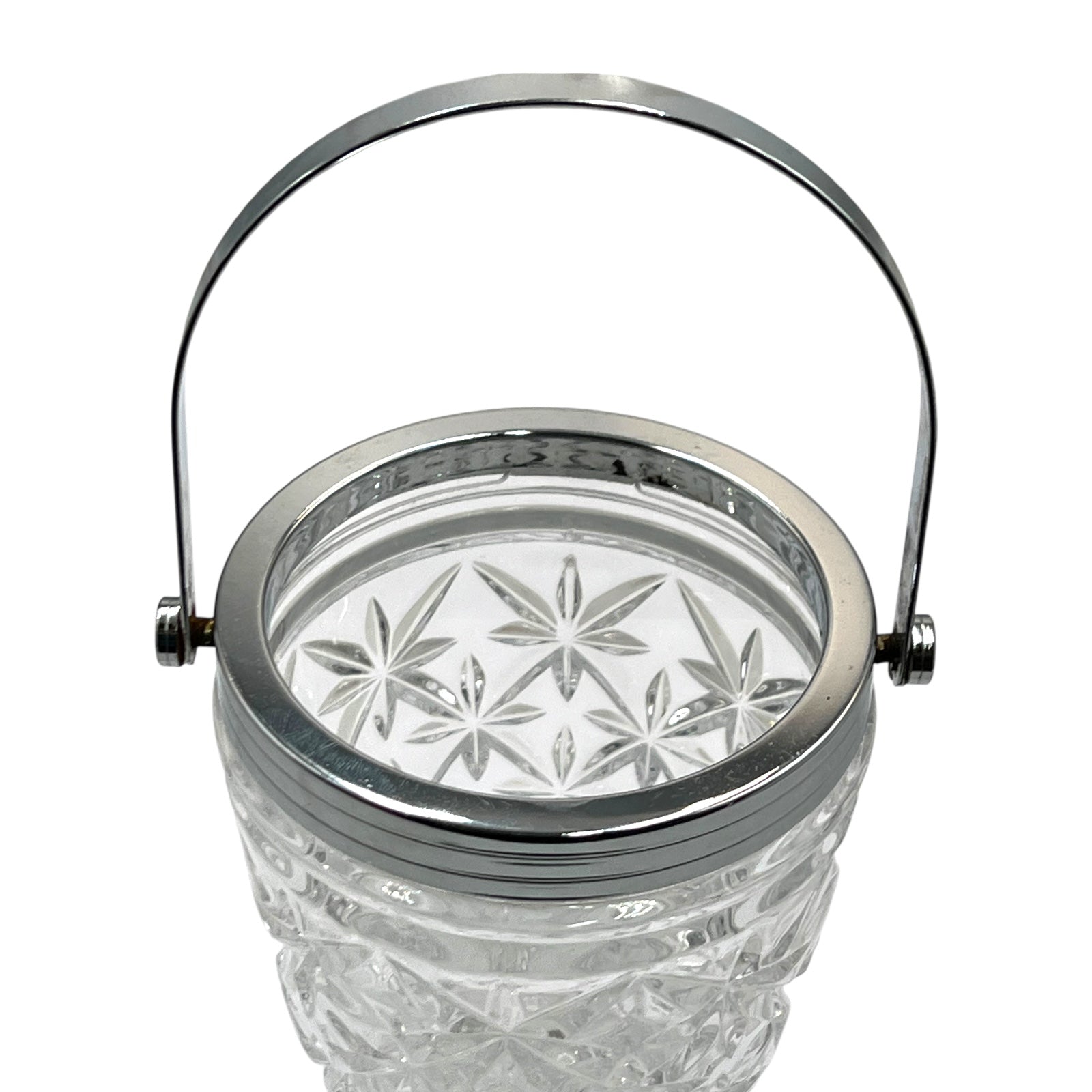 Clear French cut glass ice bucket with textured design and metal handle on a white background