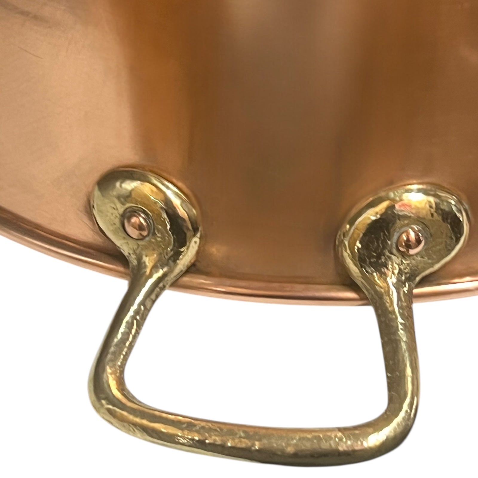 Close-up of a copper pot with brass handles on a white background