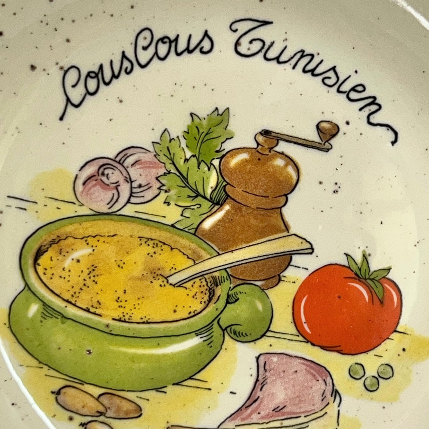 Decorative plate with illustration of couscous Tunisien and ingredients on a speckled background.