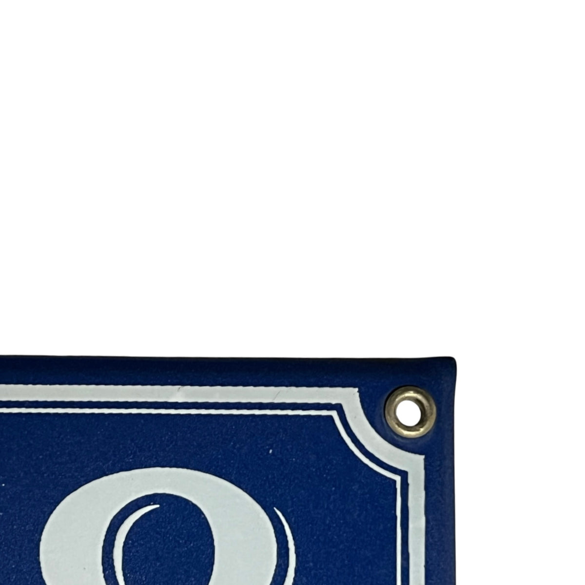Close-up of a dark blue sign or panel corner with a brass grommet and part of a white decorative border and letter visible, against a white background.