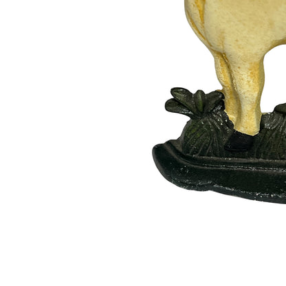 Close-up of a decorative figurine showing the lower legs of a pale cream-colored animal standing on a dark green textured base against a white background.
