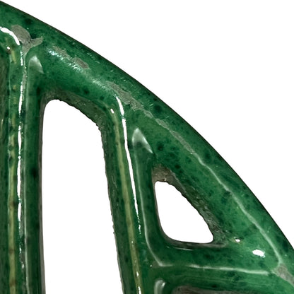 Close up of a green vintage French cast iron enamelled pan trivet on a white background