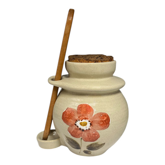 Ceramic jar with a floral design and wooden spoon on a white background