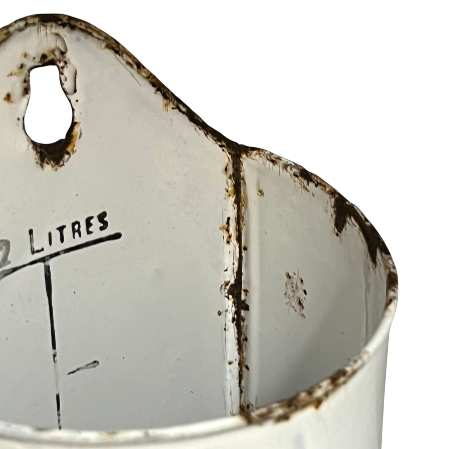 Close-up of a vintage white enamel metal pot container with rusted edges, a hanging hole, and partial black measurement text reading '2 LITRES' on a white background.