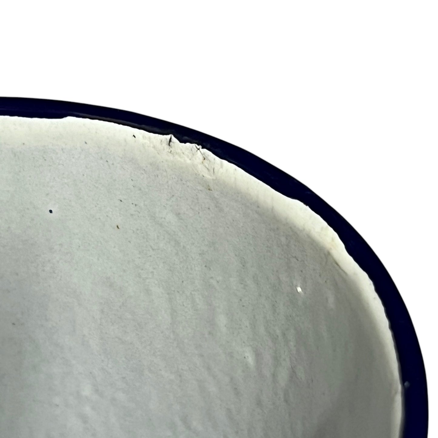 Close-up of a white enamel jug showing the textured glazed interior and a dark rim against a white background.