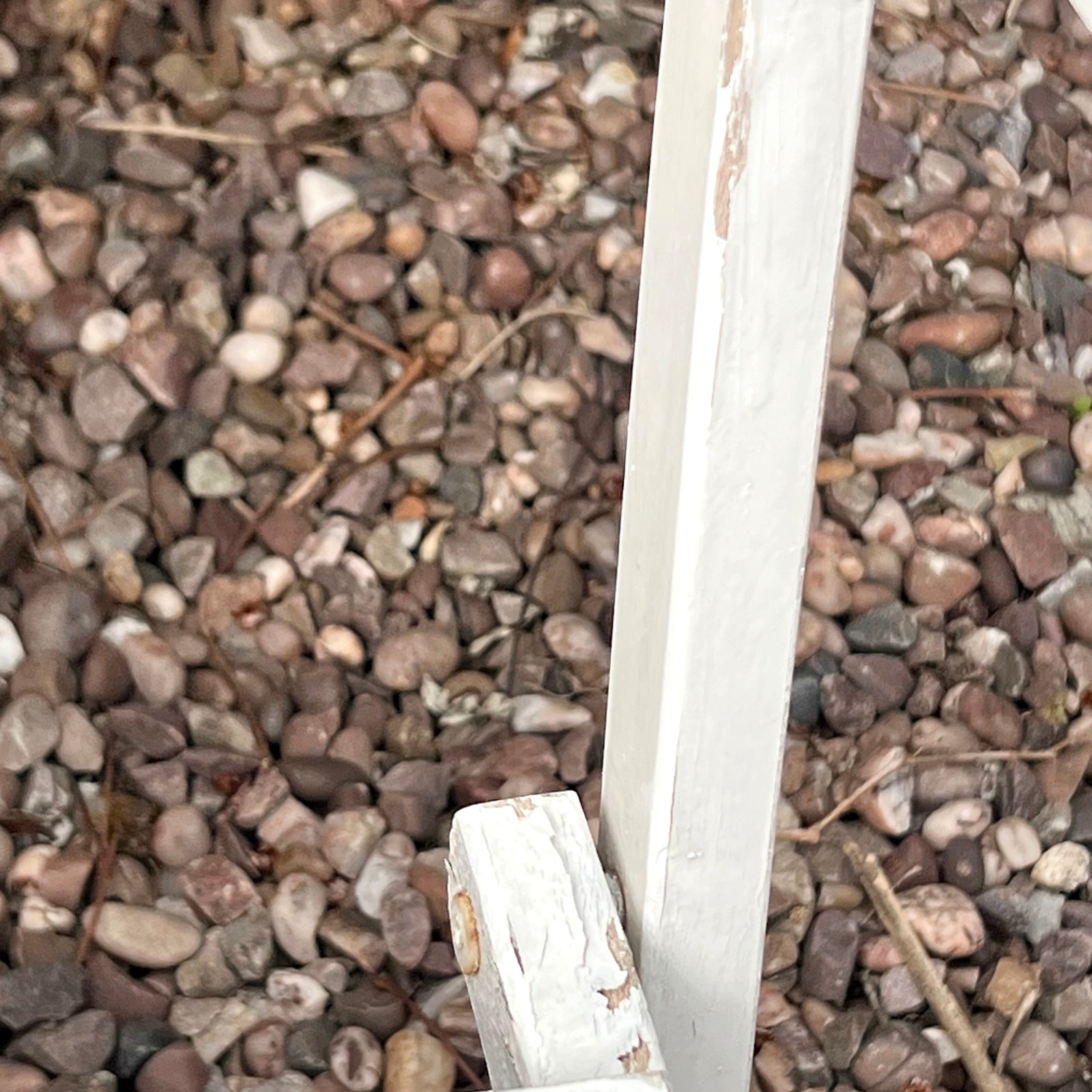 Close-up detail of French wooden slatted chairs, highlighting their condition in an outdoor setting.