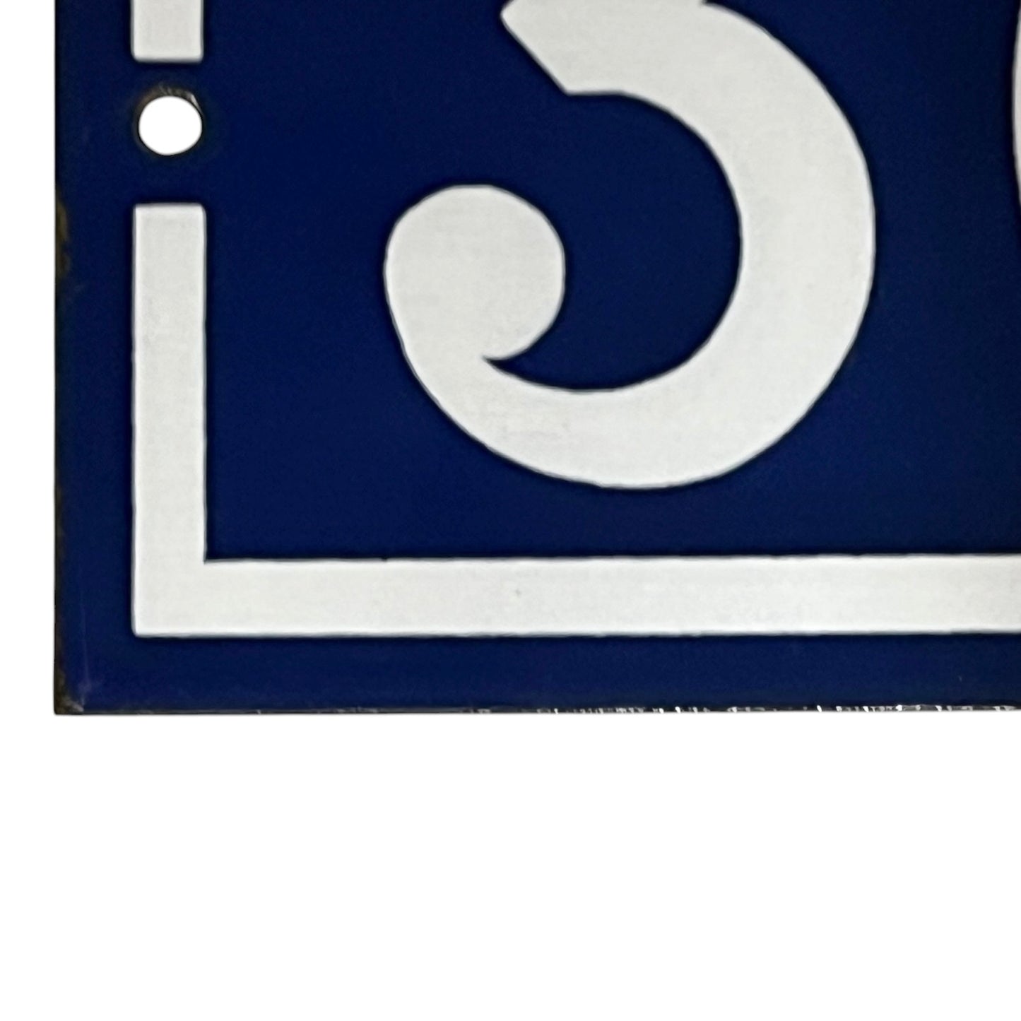Close-up of a blue and white door number on a white background
