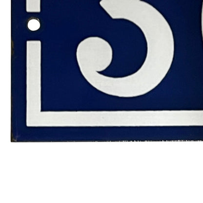 Close-up of a blue and white door number on a white background
