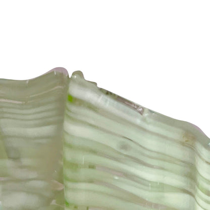 A close-up of a translucent glass lampshade material with pale green and white pattern, shown against a plain white background.