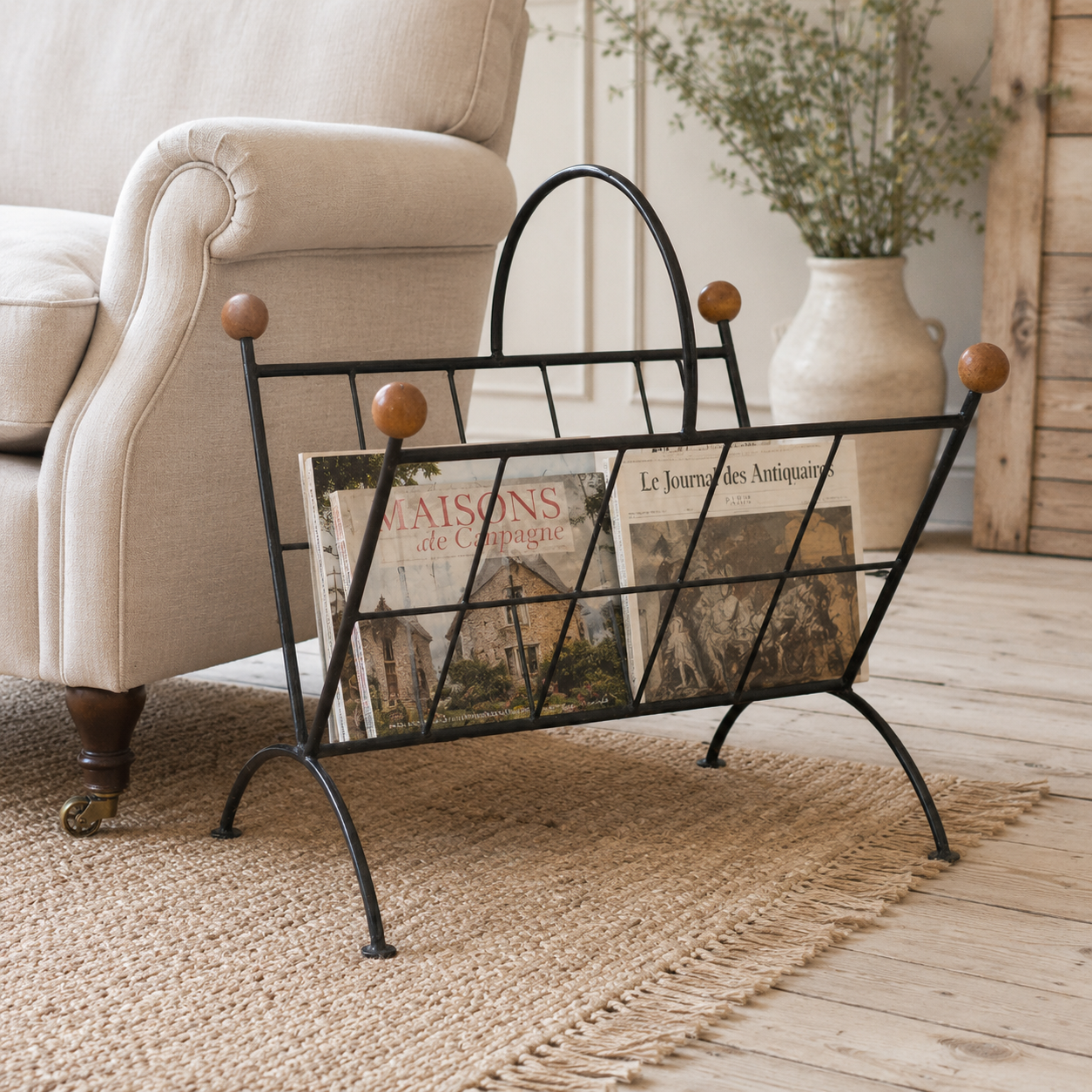 Wrought iron magazine rack with books on a wooden floor in a living room setting.