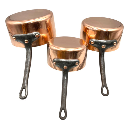 Set of three copper 2mm saucepans with new tin lining and black handles on a white background