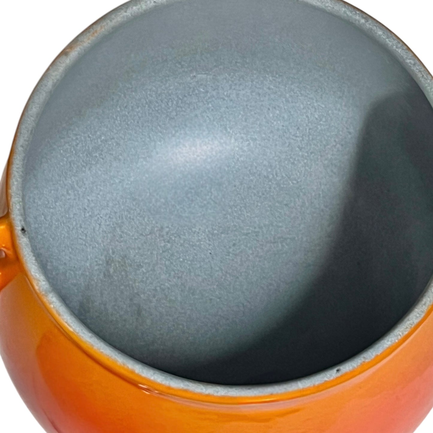 Close-up of the interior of a ceramic pot, bordered by a glossy orange exterior.