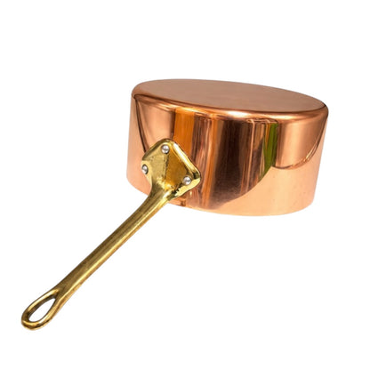 A small copper saucepan with a shiny metallic finish and a brass-colored handle, isolated on a white background.