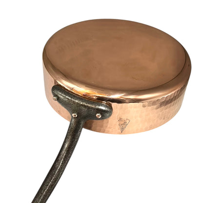 Copper pan with a black handle on a white background