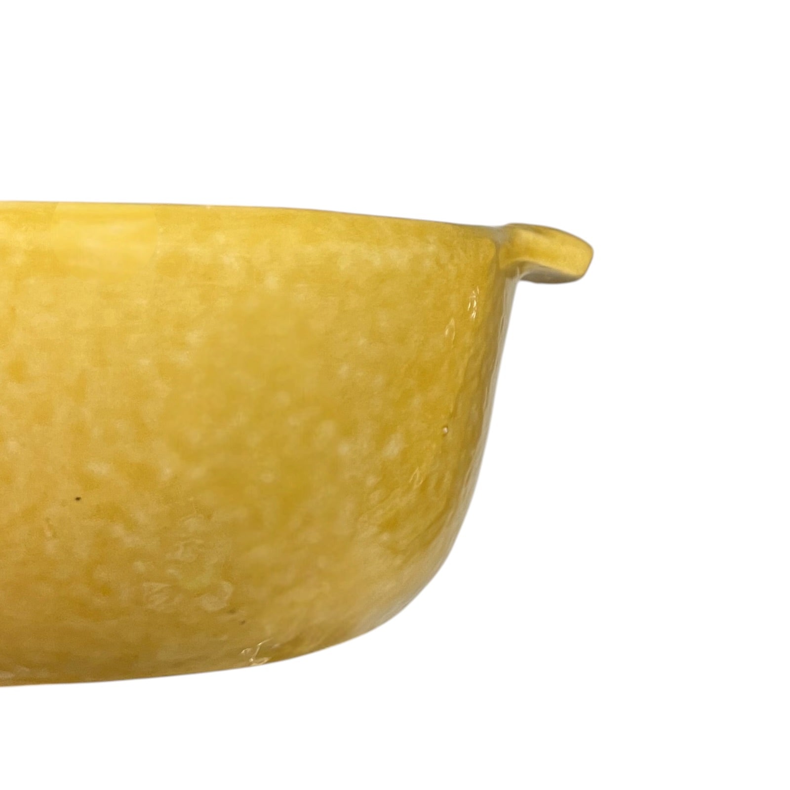 A close-up of a yellow ceramic bowl showing its textured glaze and a small side tab, isolated on a white background.