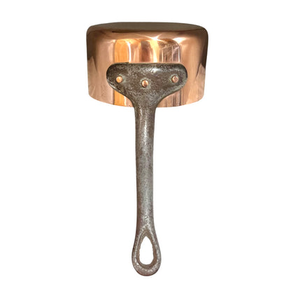 Copper saucepan with a black cast iron handle on a white background